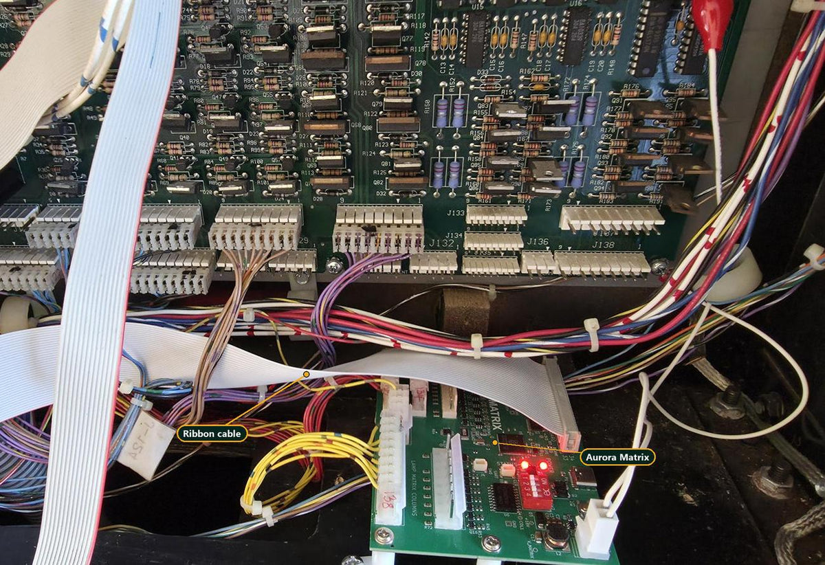 Aurora Matrix fitted below the power driver board in a WPC backbox, with the ribbon cable plugged in